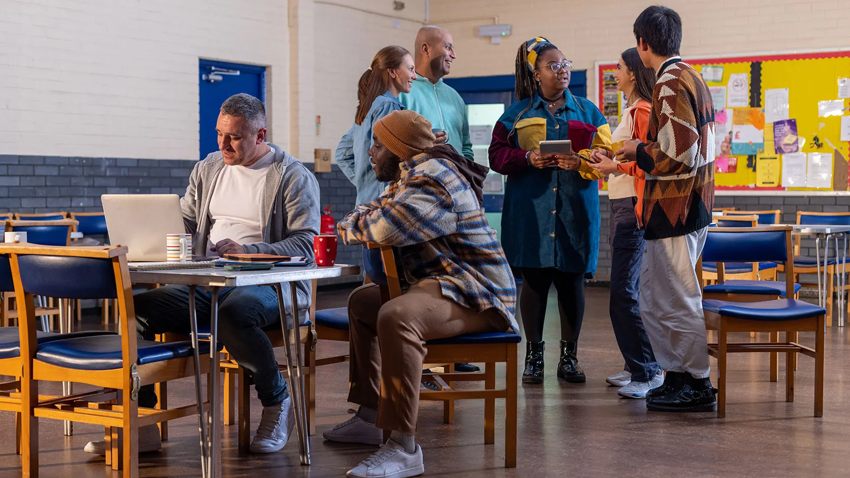 People talking and working together around a table in a community hall.